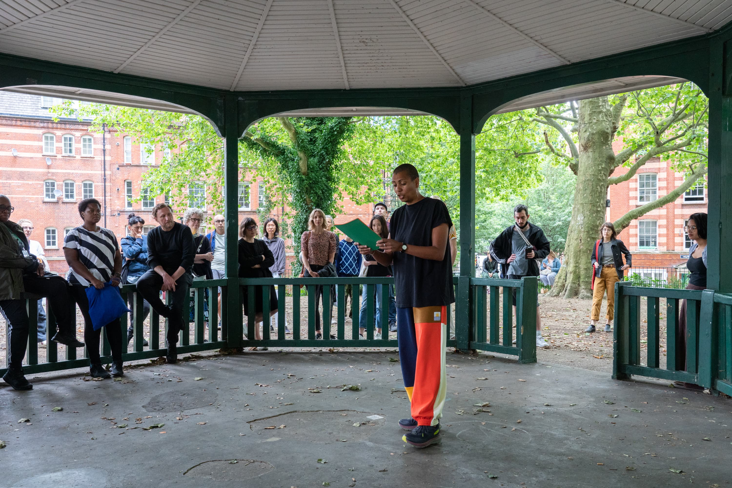 The artist Helen Cammock giving a reading of one of her perfomances. In the background is a poster that says I can hear your lament