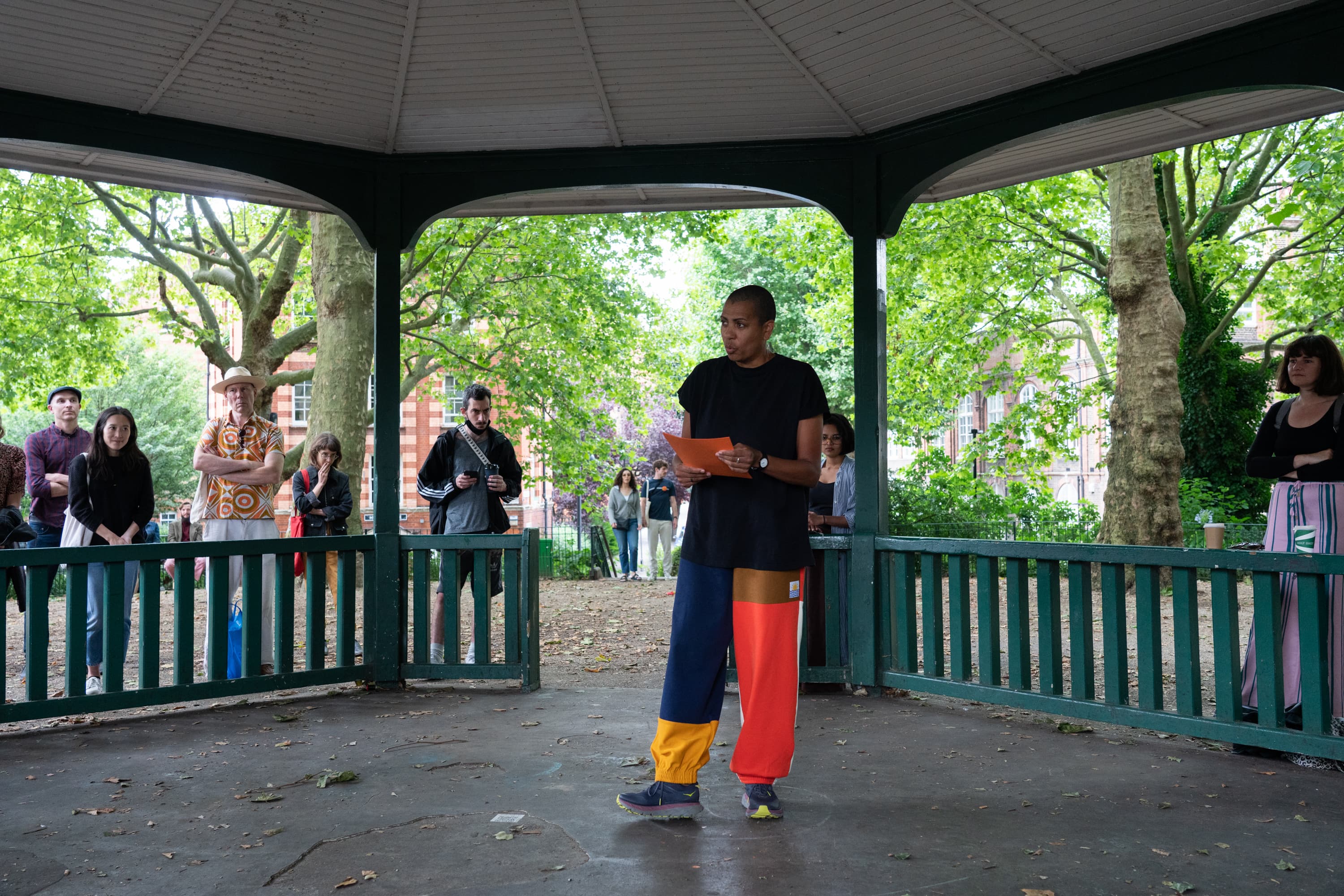 The artist Helen Cammock giving a reading of one of her perfomances. In the background is a poster that says I can hear your lament