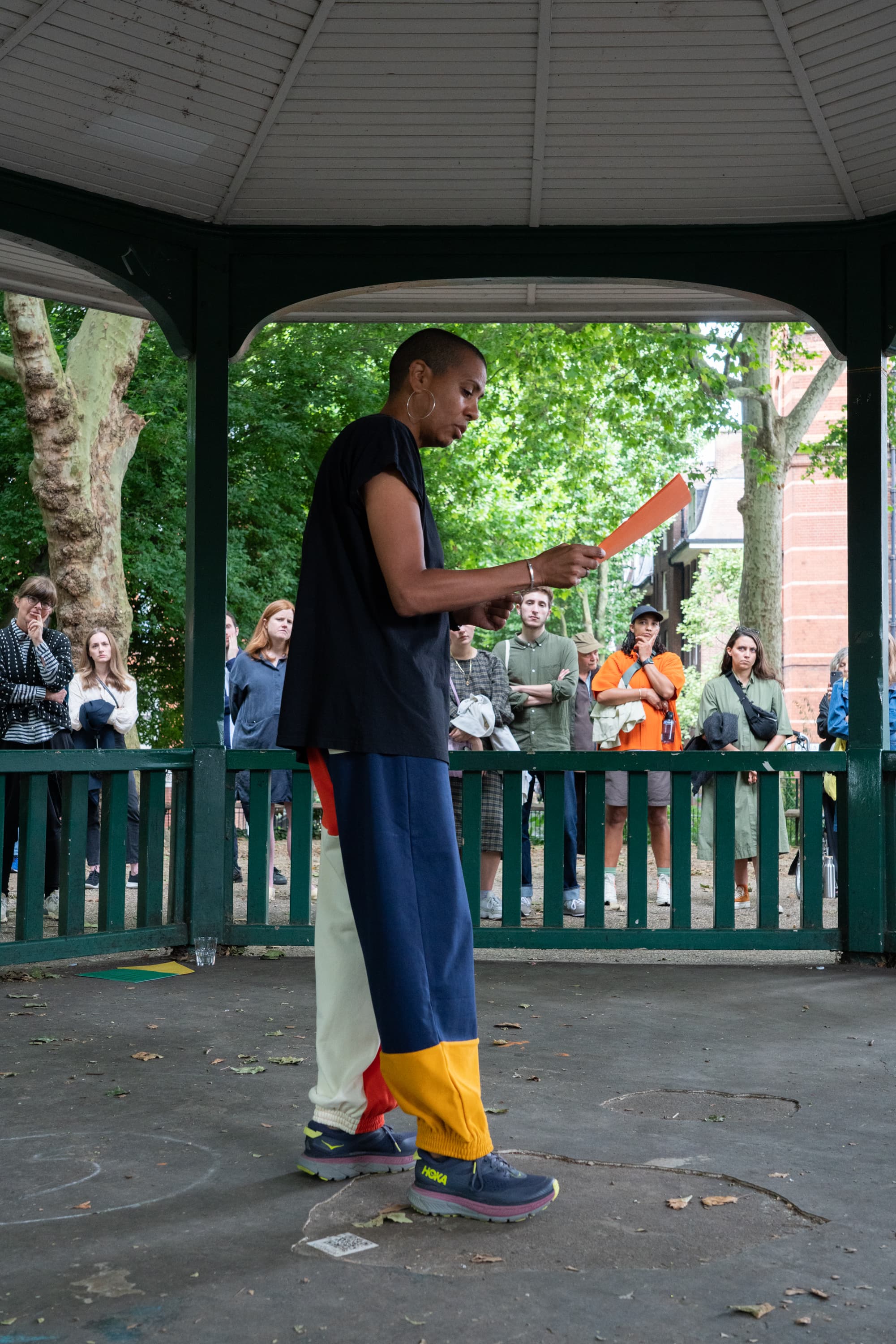 The artist Helen Cammock giving a reading of one of her perfomances. In the background is a poster that says I can hear your lament