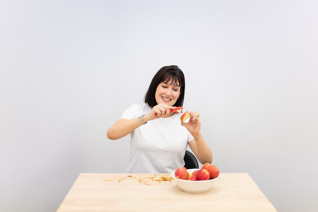 A performer sat at a table peeling an apple.