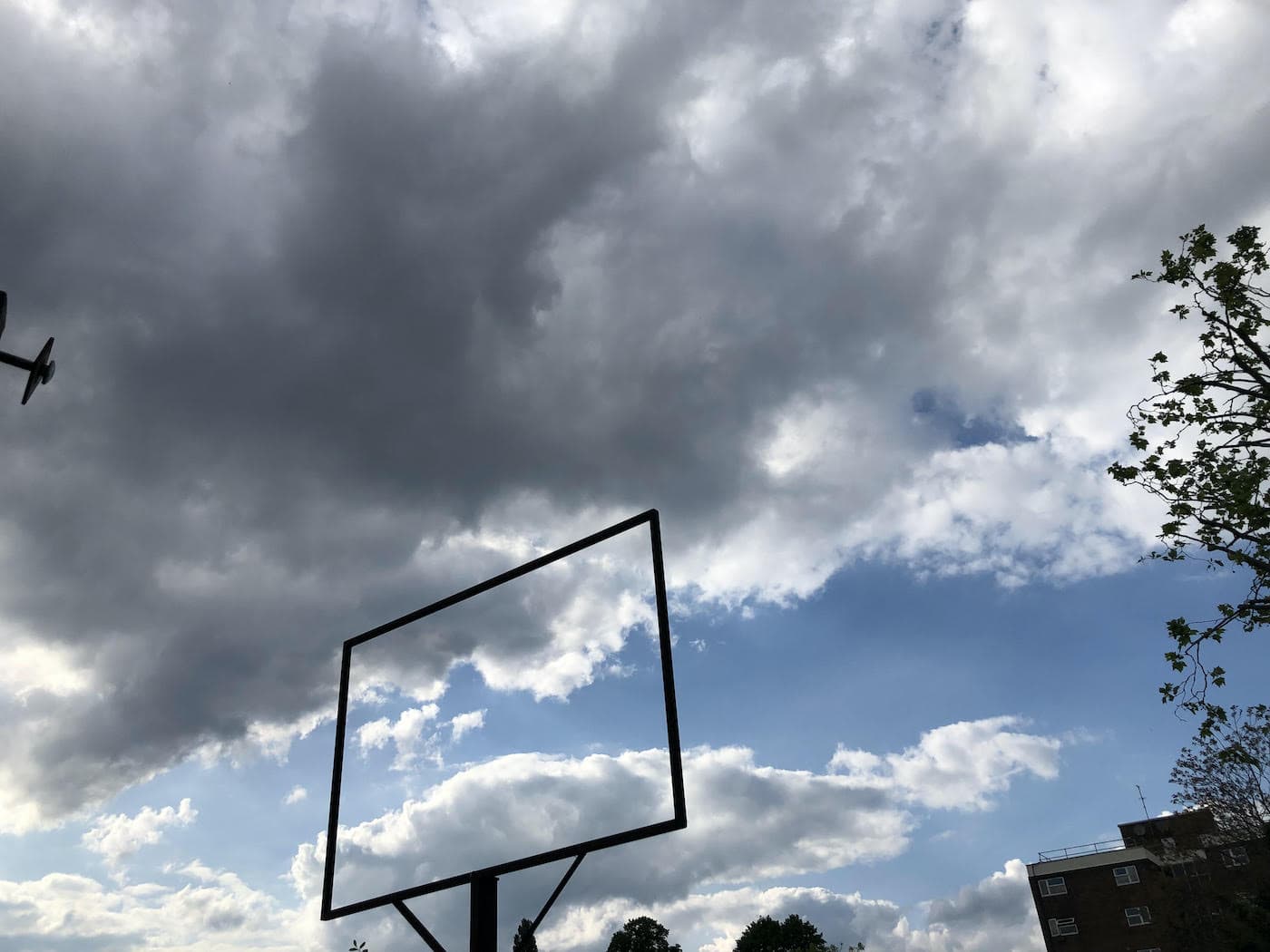 Silhouette of an old pub sign against a vast cloudy sky.