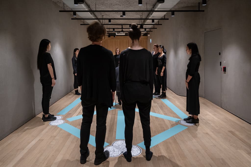 Performers, dressed in black, stood around a pentagram shape painted on the floor