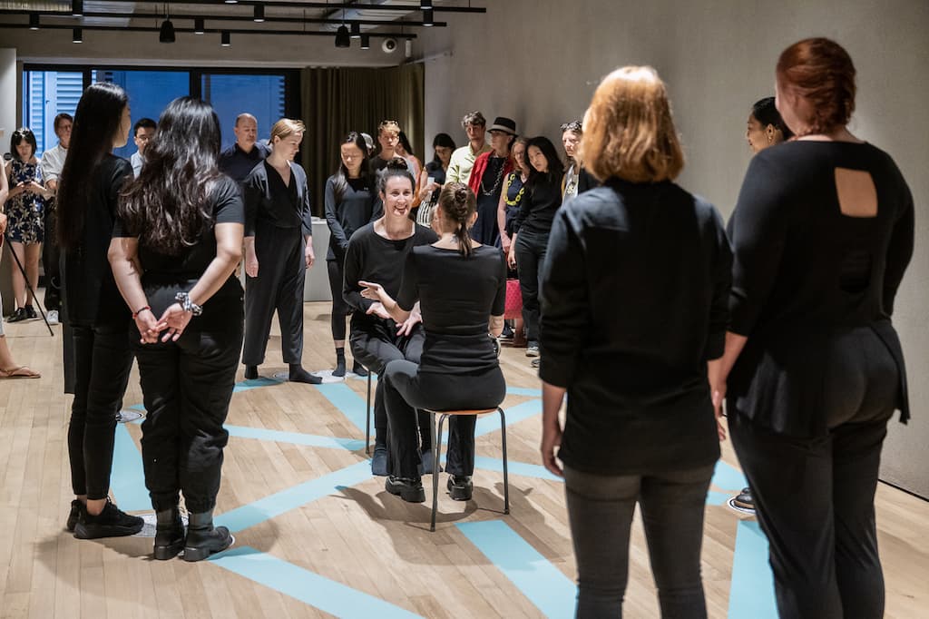 Installation shot showing two performers sat in the middle of the pentagram