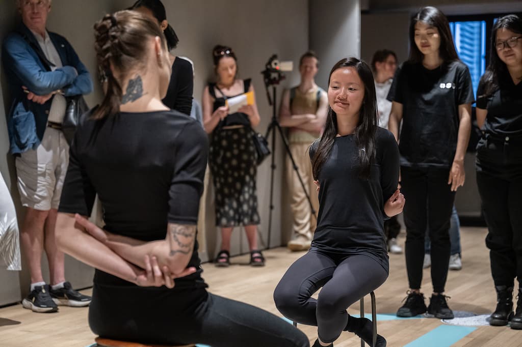 Installation shot showing two performers sat in the middle of the pentagram with their arms behind their backs